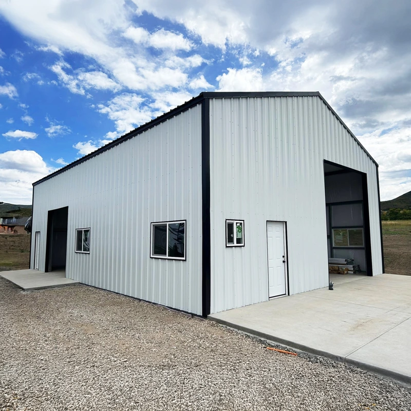 White steel shop with black trim, windows and a tall garage opening
